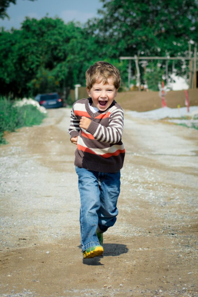 A young boy joyfully runs down a path, showcasing playful energy in a Czech outdoor setting.